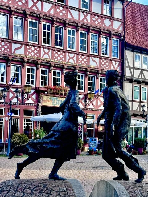 Bronzeskulptur vor rotem Fachwerkhaus